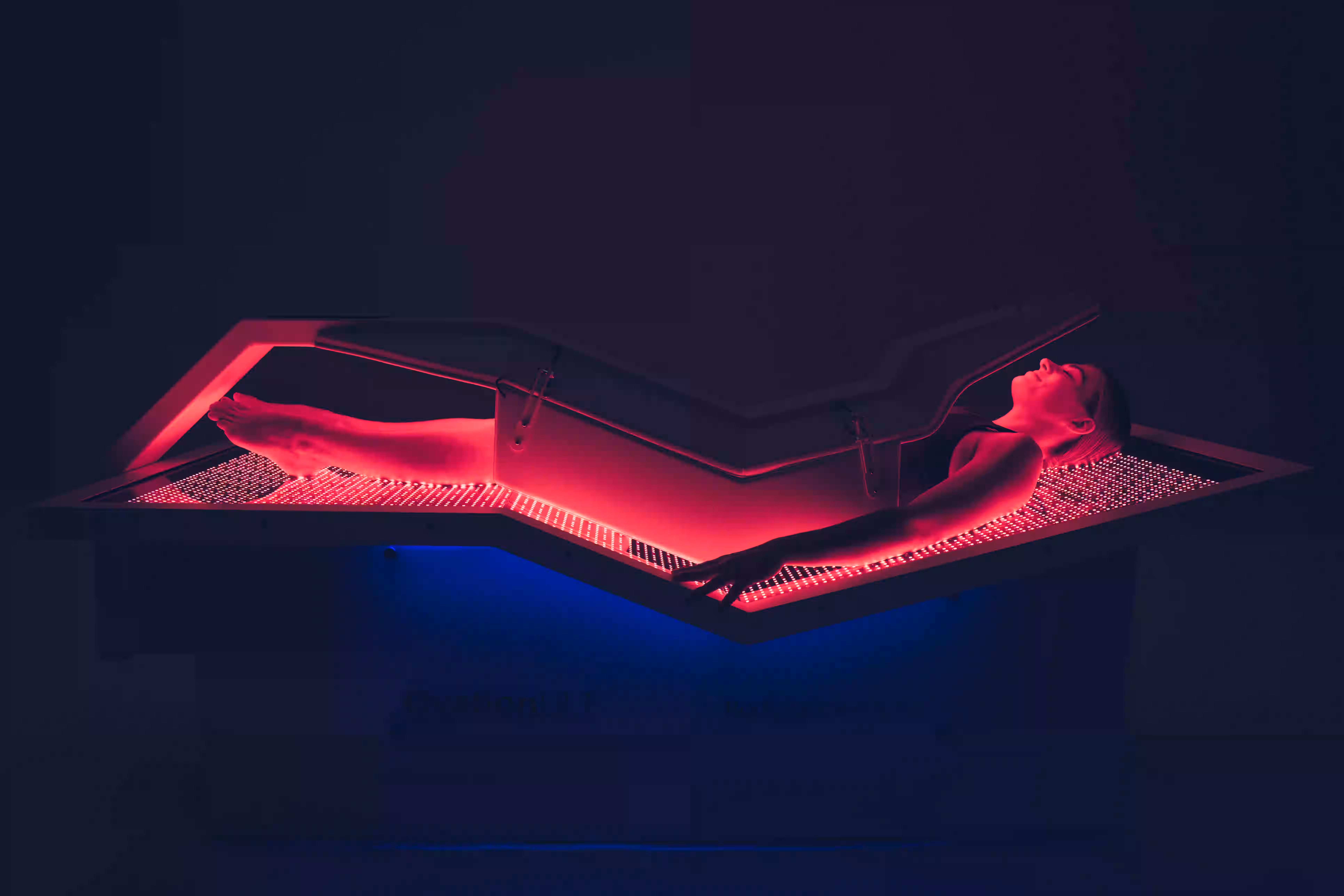 Woman using OvationULT commercial red light therapy bed for wellness treatment